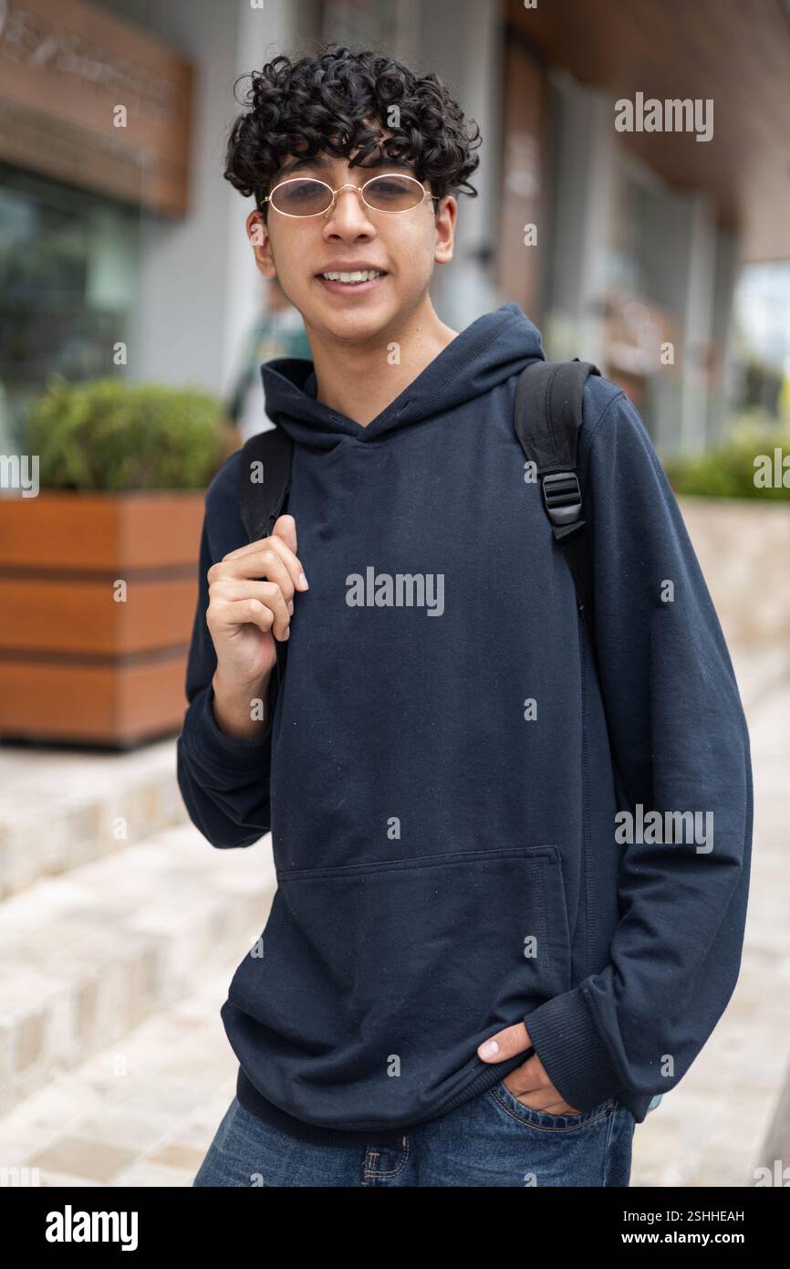 Un giovane che cammina per la città dopo aver studiato, perfetto per temi come la vita studentesca, lo stile di vita urbano, il relax e i momenti post-studio. Foto Stock