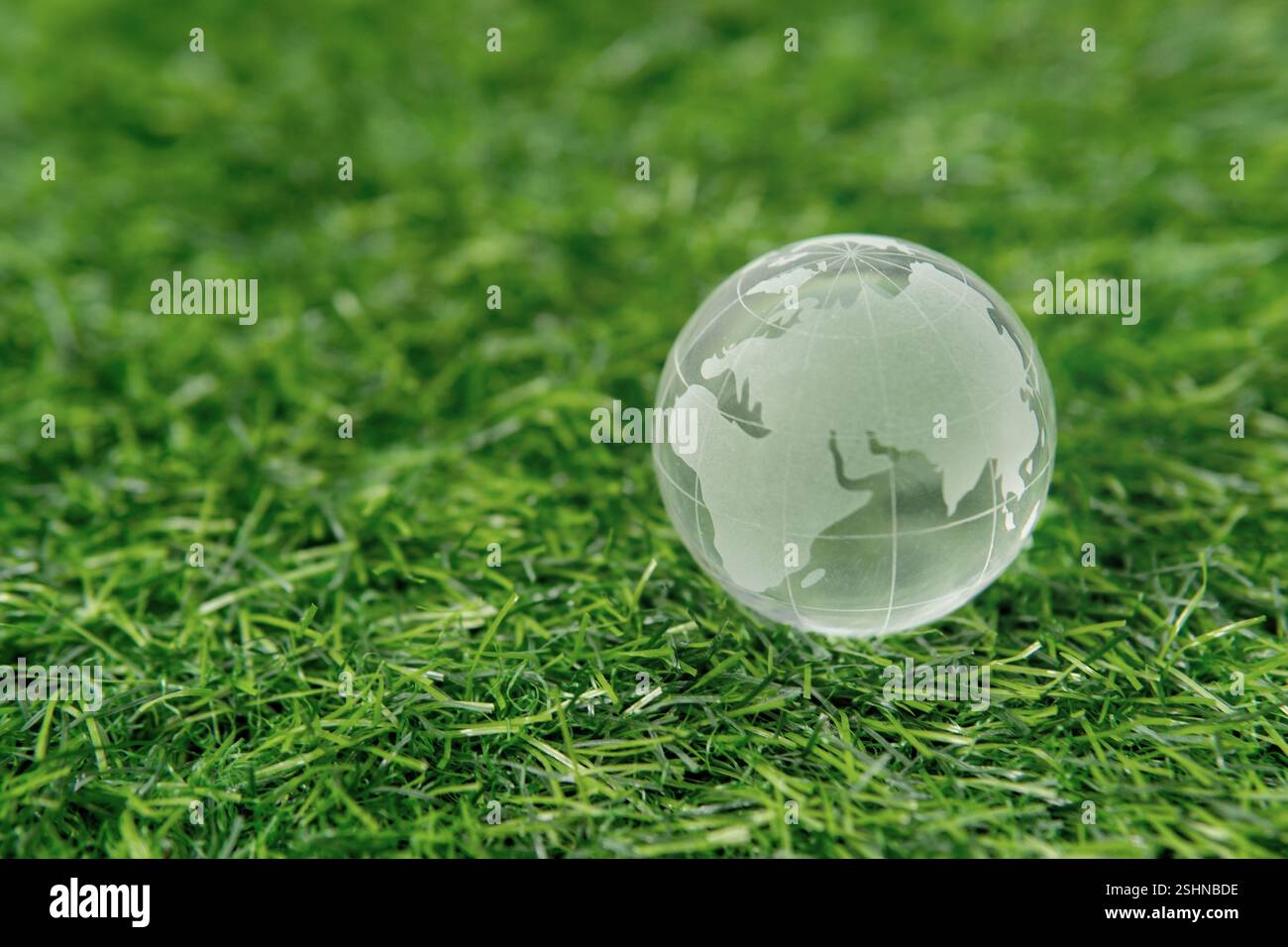 Un globo di cristallo su un'erba verde. Protezione dell'ambiente, sostenibilità, concetto della giornata della Terra. Copia spazio per il testo. Foto Stock