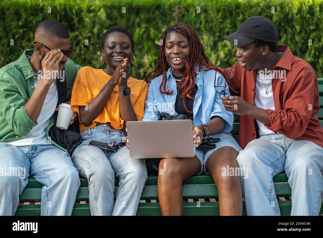 Gruppi multiculturali di amici che guardano film su un computer portatile nel parco, rilassati e goditi il fine settimana all'aperto Foto Stock