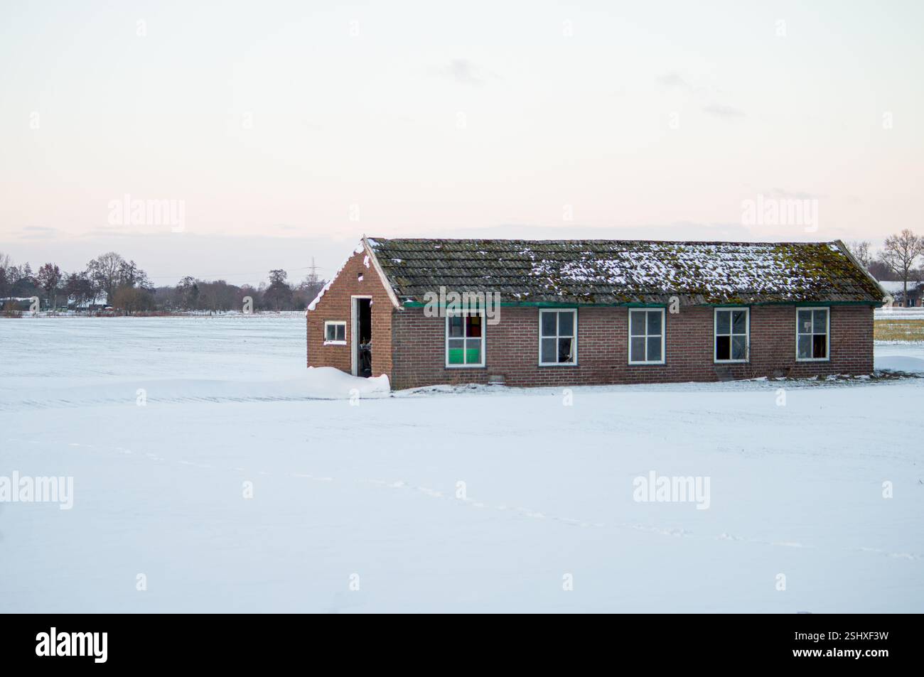 In campagna si trova questo vecchio fienile in pietra. La terra è ricoperta di neve durante l'inverno Foto Stock