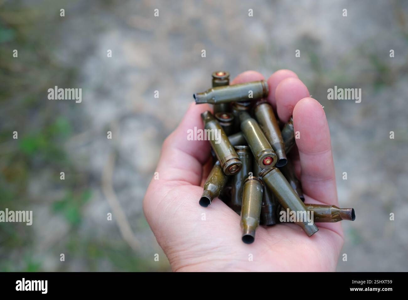 Involucri di proiettili nella mano umana. Svuotare le coperture sul terreno. L'Ucraina è una zona pericolosa. Foto Stock