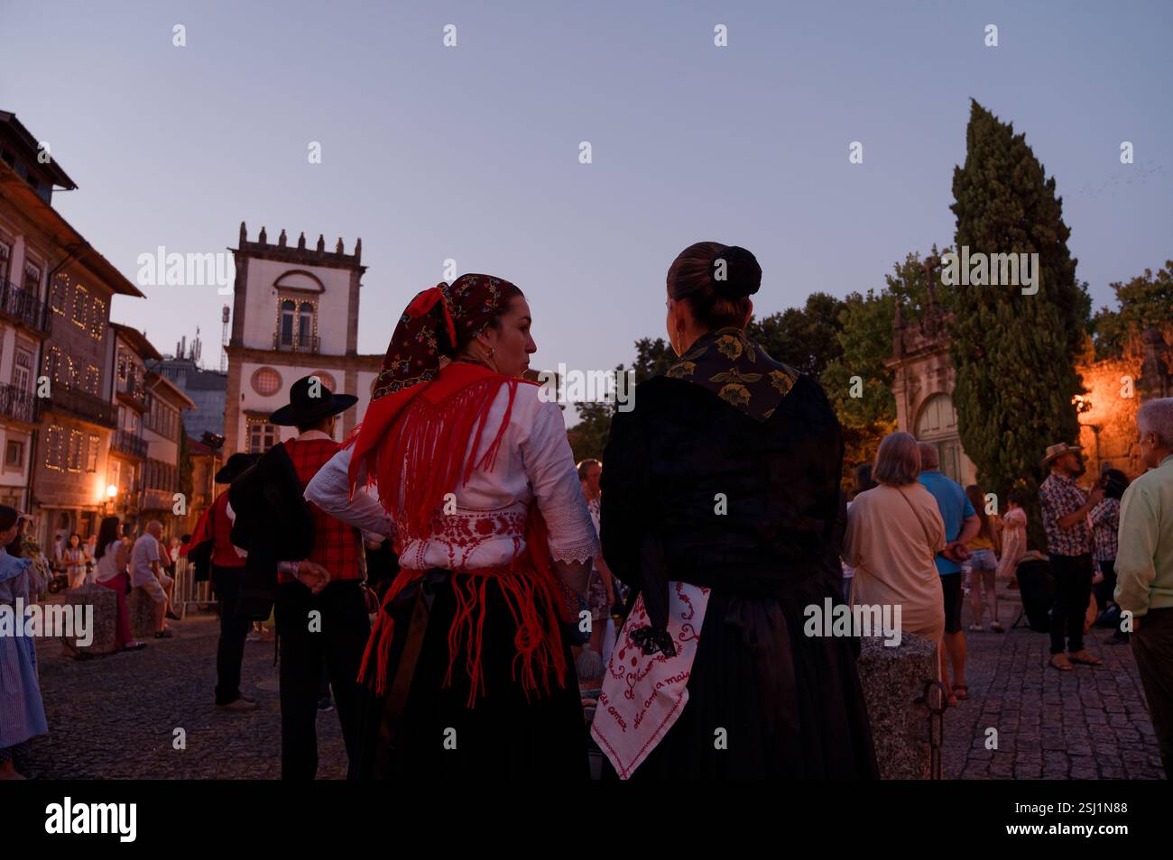 Due donne in scialli luminosi condividono un momento crepuscolo durante le Festas Gualterianas Foto Stock