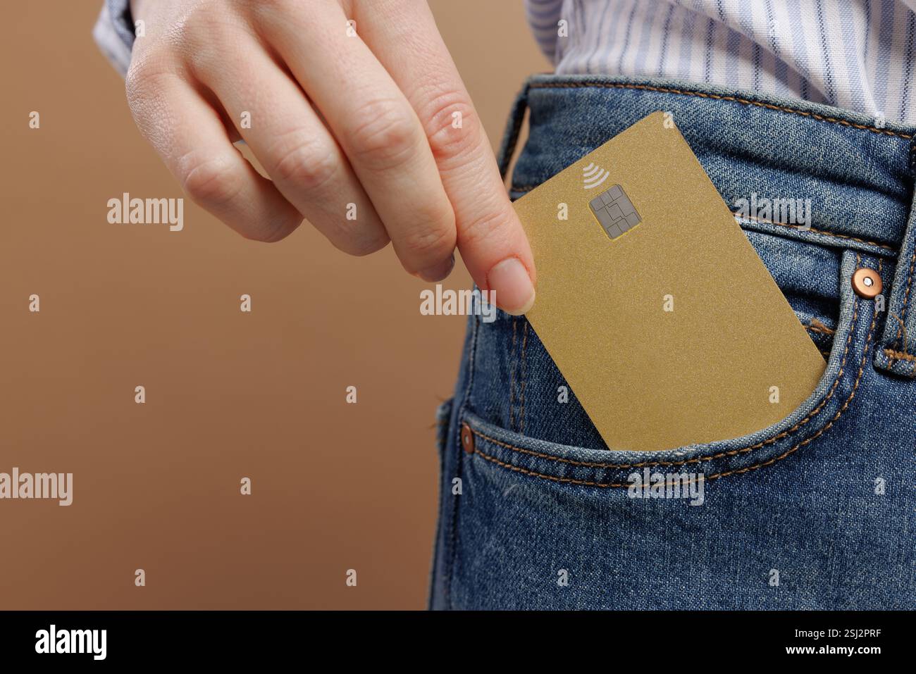 Primo piano corto di una donna vestita con abiti casual che reggono un modello di carta di credito in tasca ai jeans, Foto Stock