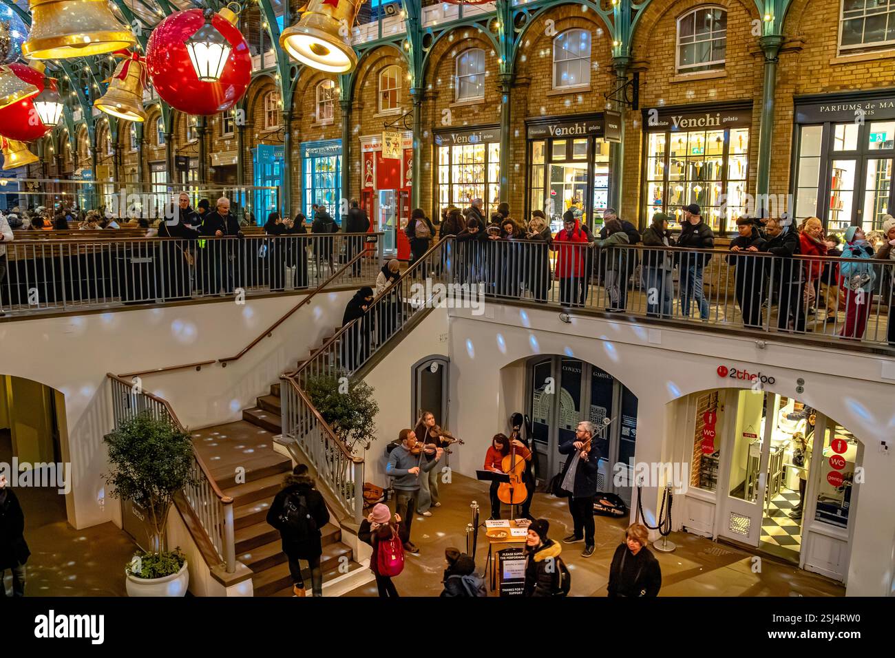 Persone che guardano musicisti che suonano nella South Hall a Natale a Covent Garden, un centro commerciale e di intrattenimento a Londra, WC1, Regno Unito Foto Stock