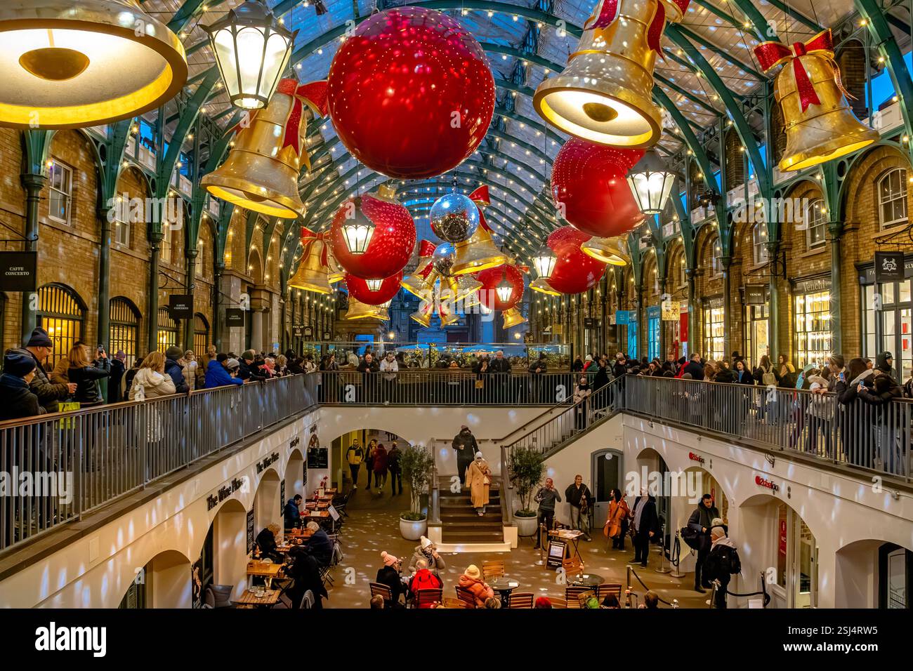 Persone che guardano musicisti che suonano nella South Hall a Natale a Covent Garden, un centro commerciale e di intrattenimento a Londra, WC1, Regno Unito Foto Stock