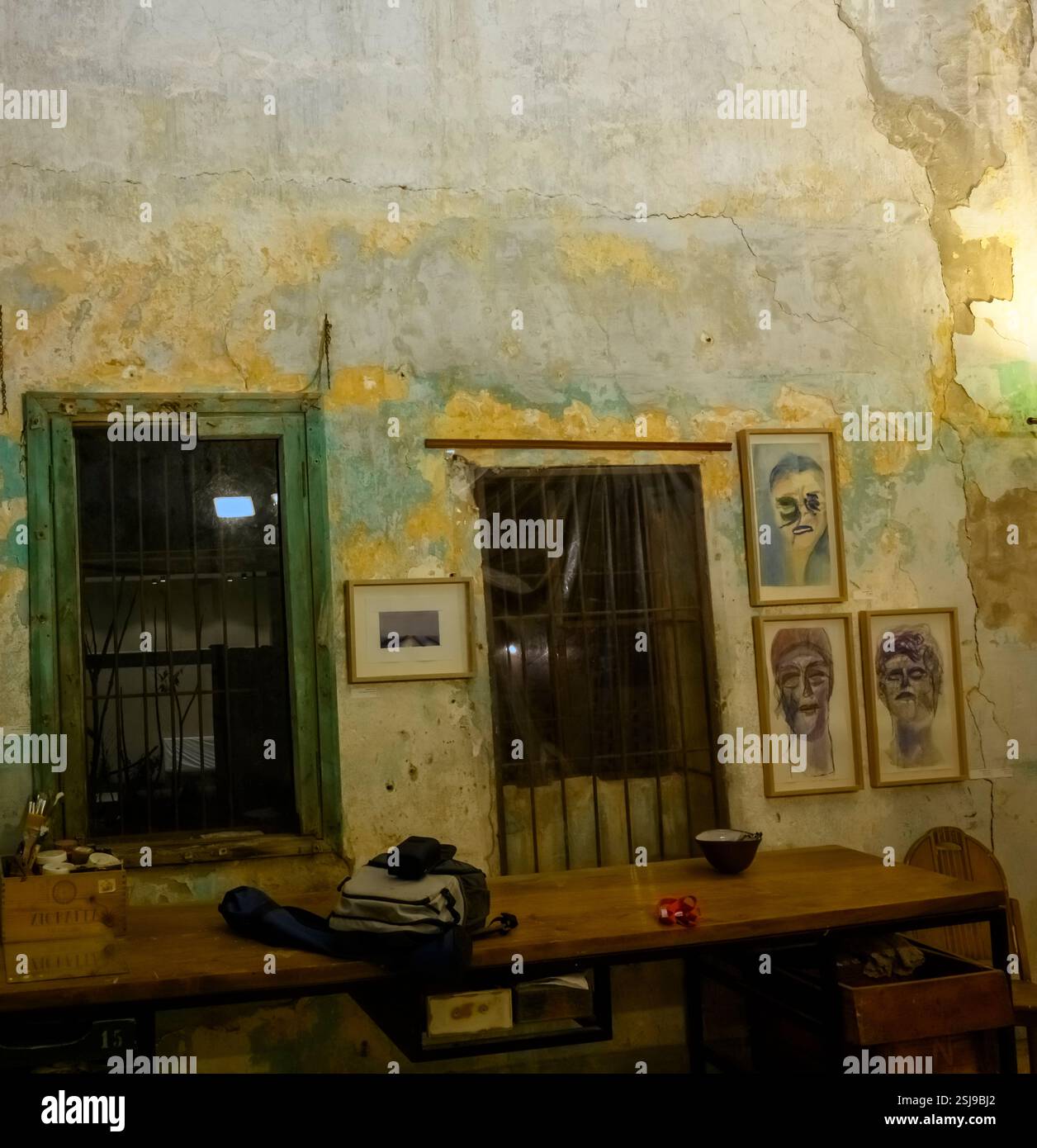 All'interno di una vecchia casa fatiscente, la parete incrinata presenta tracce di intonaco vecchio e sulla parete esterna umida si possono vedere crescere stampi di vernice Foto Stock
