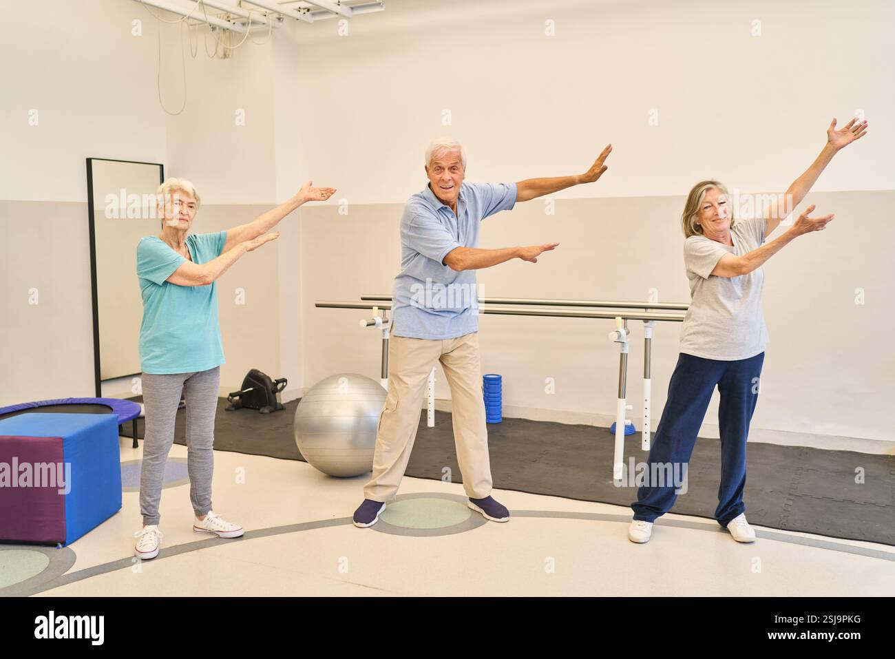 Tre anziani impegnati in attività fisica presso una struttura di riabilitazione, promuovendo salute e vitalità. Foto Stock