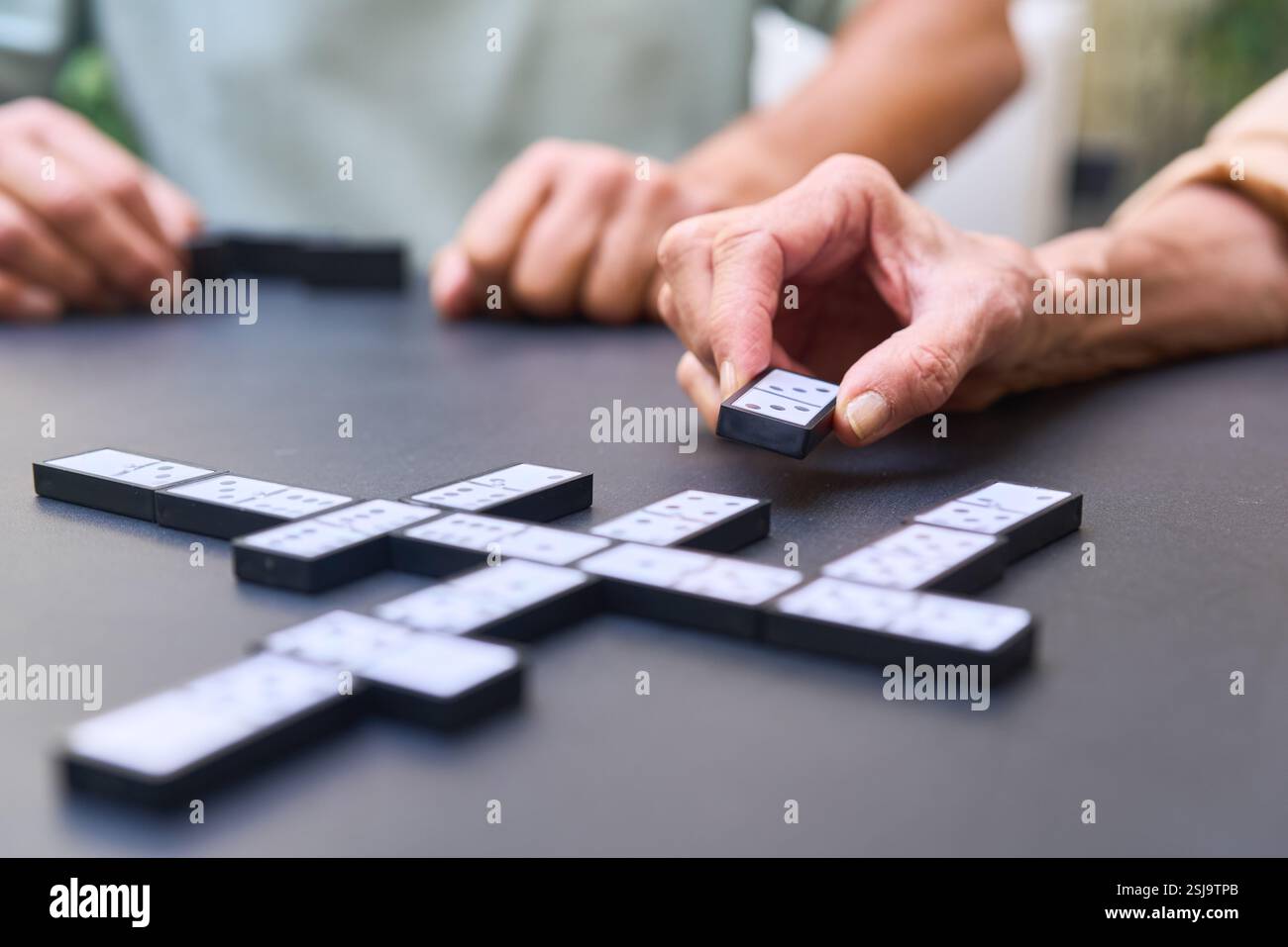 Due persone senior giocano a un gioco di domino, concentrandosi e godendosi il loro tempo insieme. L'attività incoraggia la collaborazione, l'agilità mentale, a Foto Stock