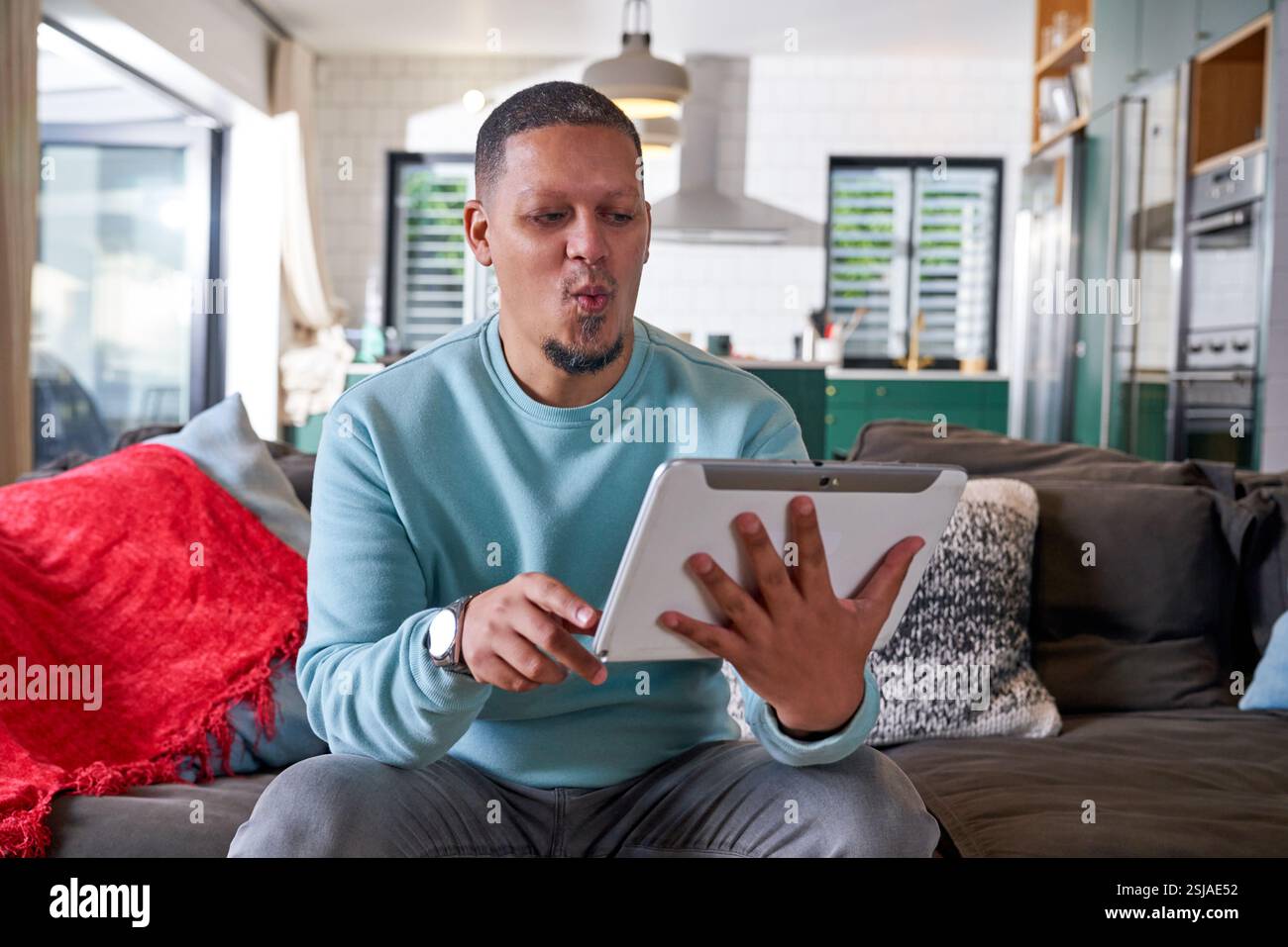 Uomo che guarda un tablet digitale sul divano Foto Stock