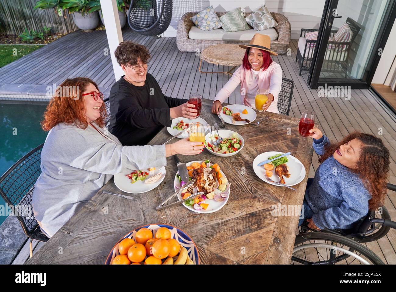 Amici sorridenti che brindano con bevande sul patio Foto Stock