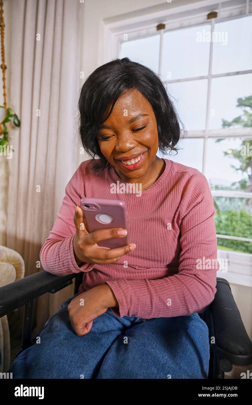 Donna in sedia a rotelle che guarda uno smartphone Foto Stock