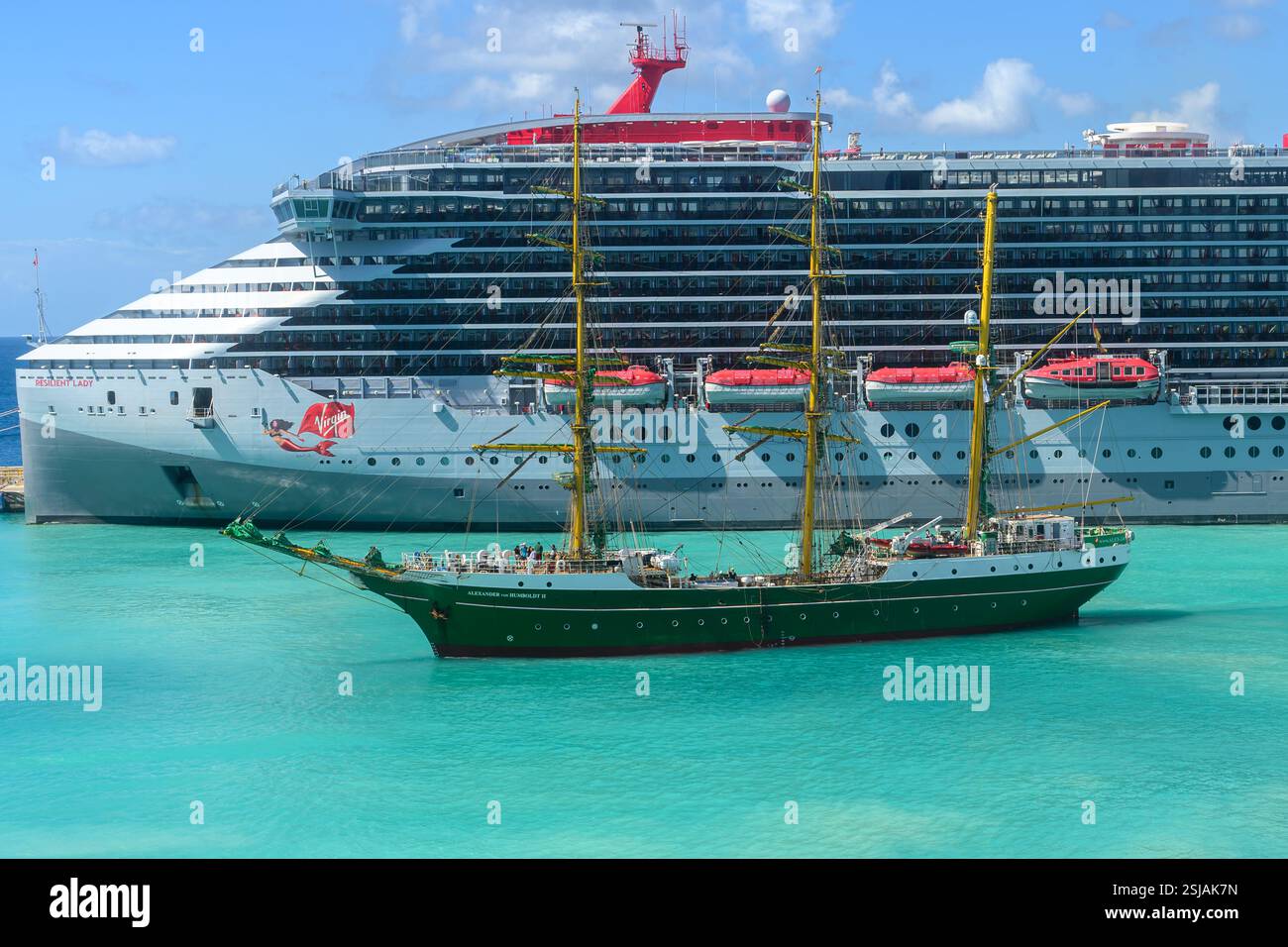 La nave di addestramento della Deutsche Stiftung Alexander von Humboldt II entra nel porto crocieristico di Bridgetown, alle Barbados, con Virgin Resilient Lady sullo sfondo Foto Stock