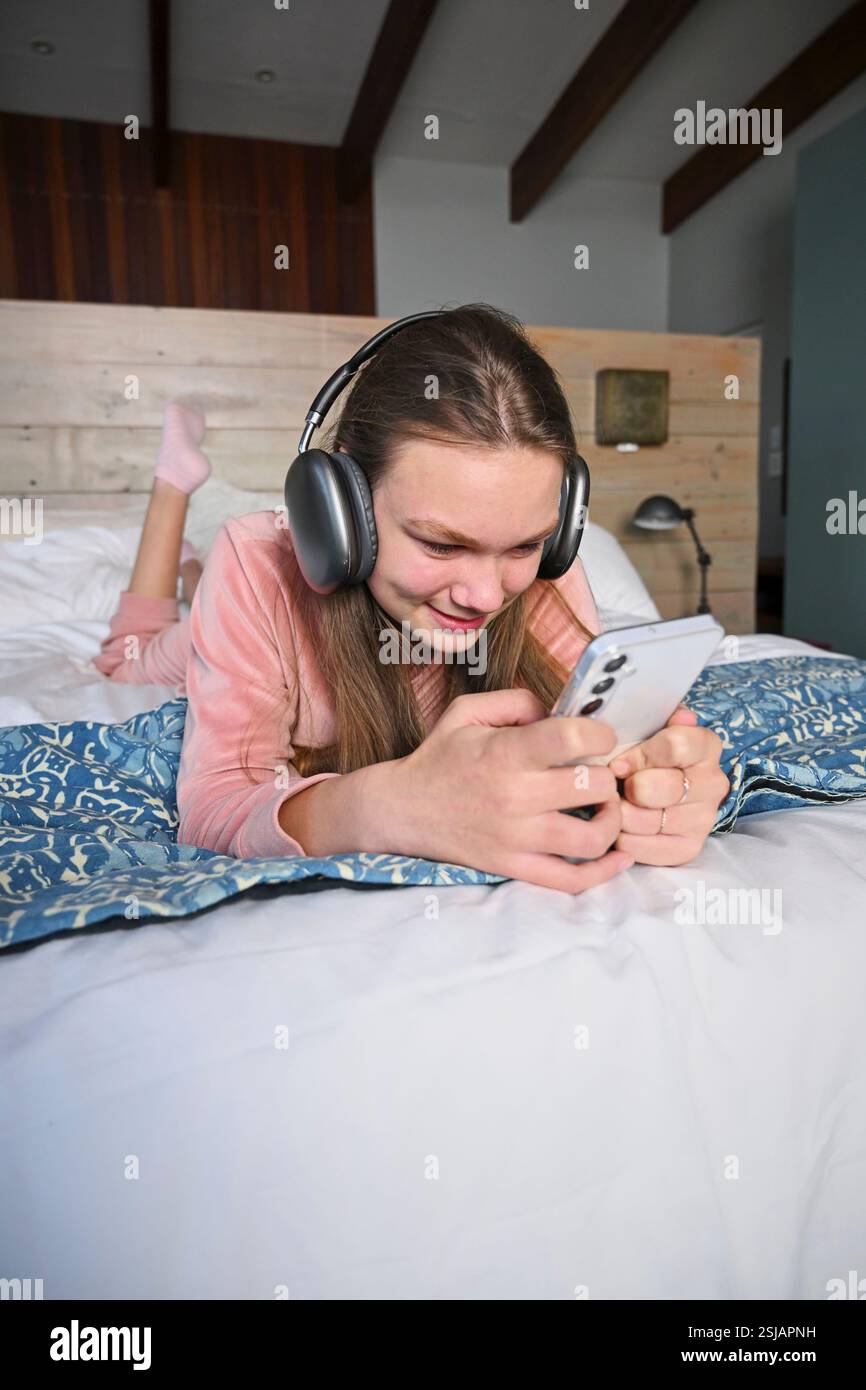 Ragazza sorridente (12-13) che ascolta musica a letto Foto Stock