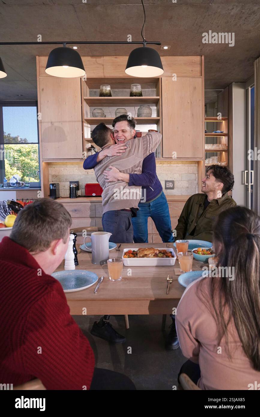 Uomini sorridenti che abbracciano a casa Foto Stock