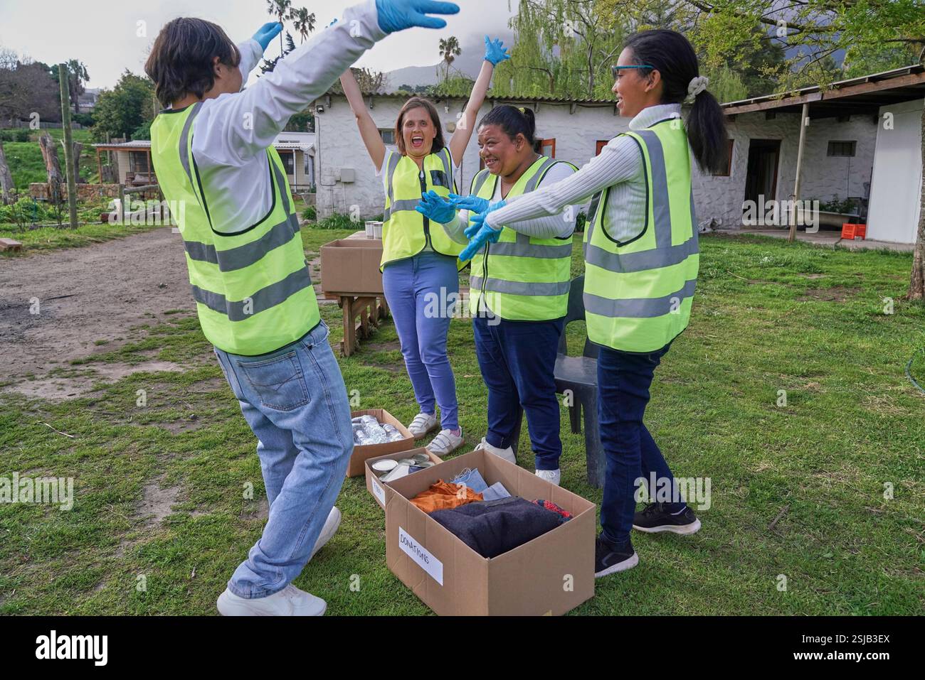 Gruppo di volontari in piedi con le mani alzate sopra le scatole per donazioni all'aperto Foto Stock