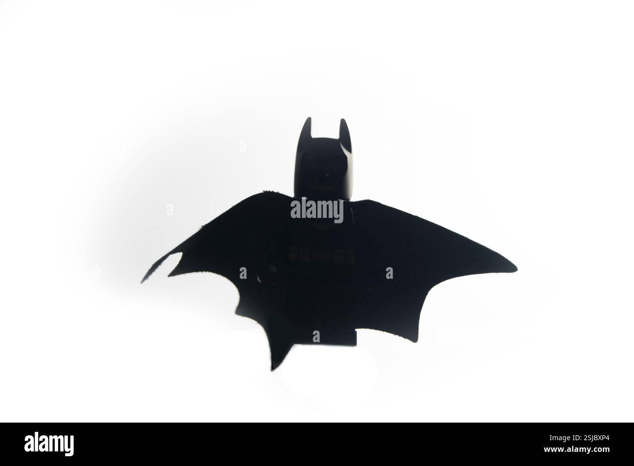 Minifigure LEGO Batman in una spettacolare posa di volo con mantello largo, isolato su uno sfondo bianco. Iconico giocattolo supereroe catturato con una luce dinamica Foto Stock