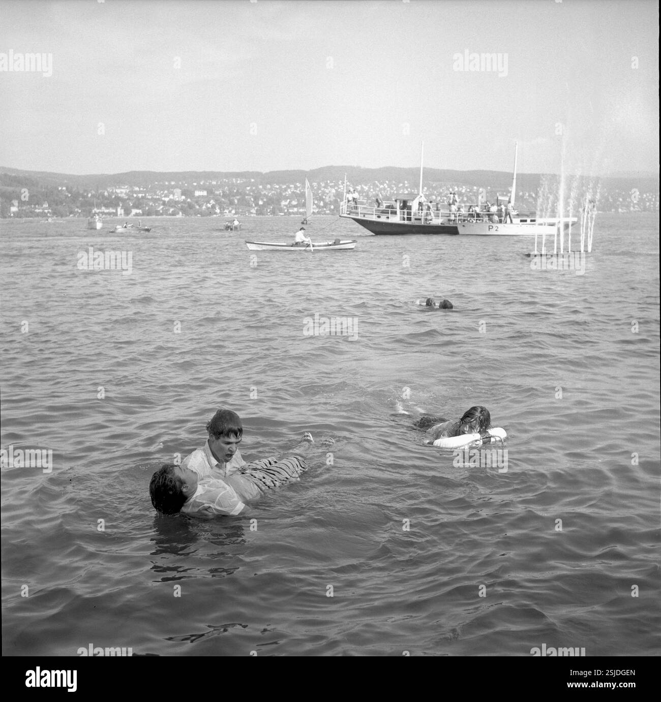 Im Rahmen einer gestellten Schiffsexplosion stürzten sich die 'passagiere' ins Wasser und wurden von Rettungsschwimmern geborgen und an Land medizinisch betreut#l'addestramento includeva una falsa esplosione di una barca sulla quale i "passeggeri" saltarono in mare e furono salvati dal bagnino. Sono stati poi curati dal medico a terra.--- Rettungsübung am 'Rotkreuztag' der SAFFA 1958#addestramento di soccorso nel 'giorno della Croce Rossa' della fiera SAFFA 1958- RDB DI DUKAS Foto Stock