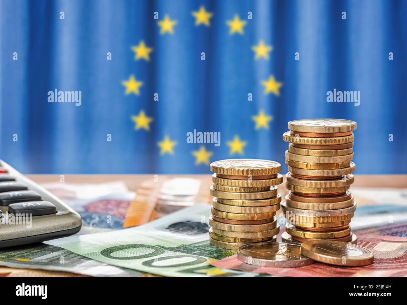 Le banconote e le monete in euro di fronte la bandiera dell'Unione europea Foto Stock