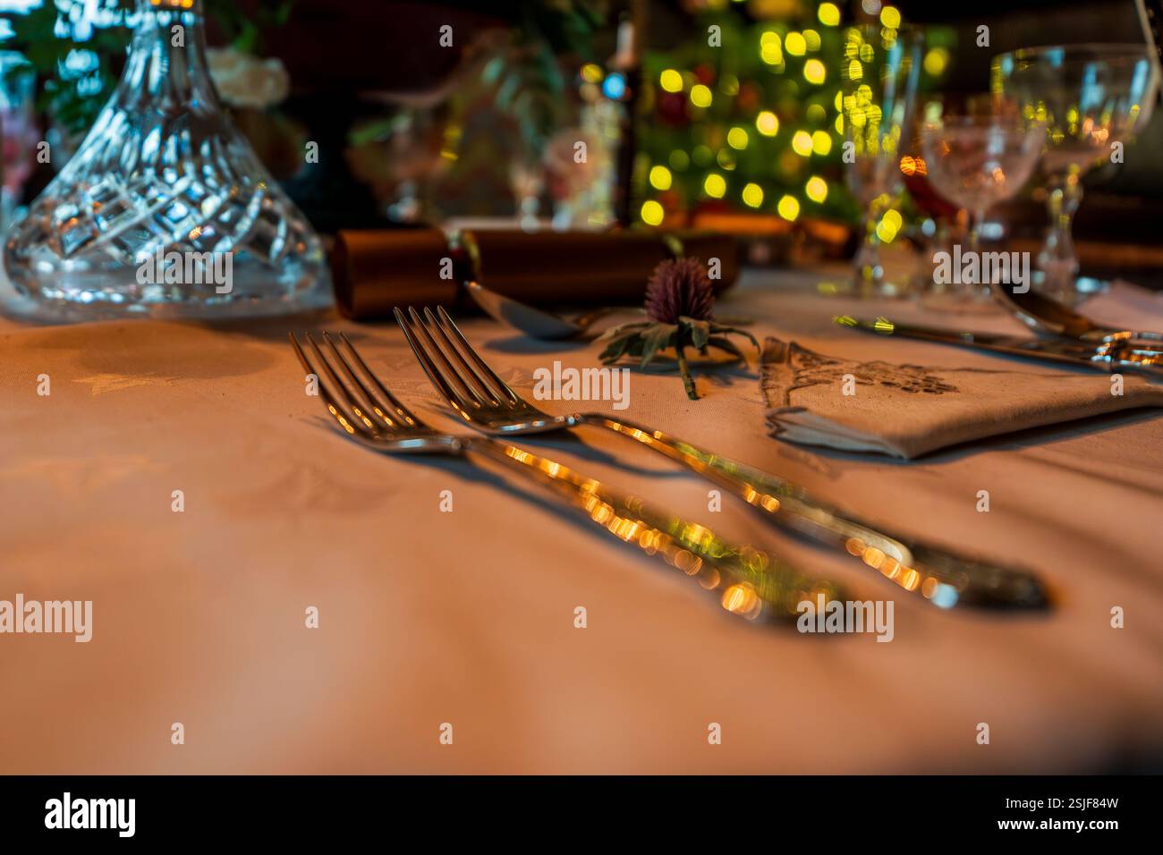 Elegante tavolo per feste con bicchieri di cristallo, posate e luci natalizie d'ambiente Foto Stock