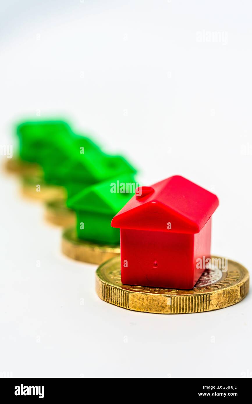 Concetto di investimento immobiliare con case collocate su monete in una lunga fila Foto Stock