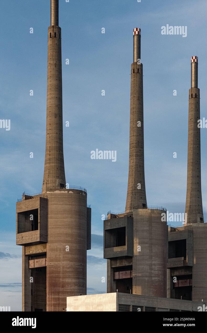I tre imponenti camini della vecchia centrale termica di Sant Adrià de Besòs si stagliano sullo sfondo di un cielo blu, che getta lunghe ombre. Foto Stock