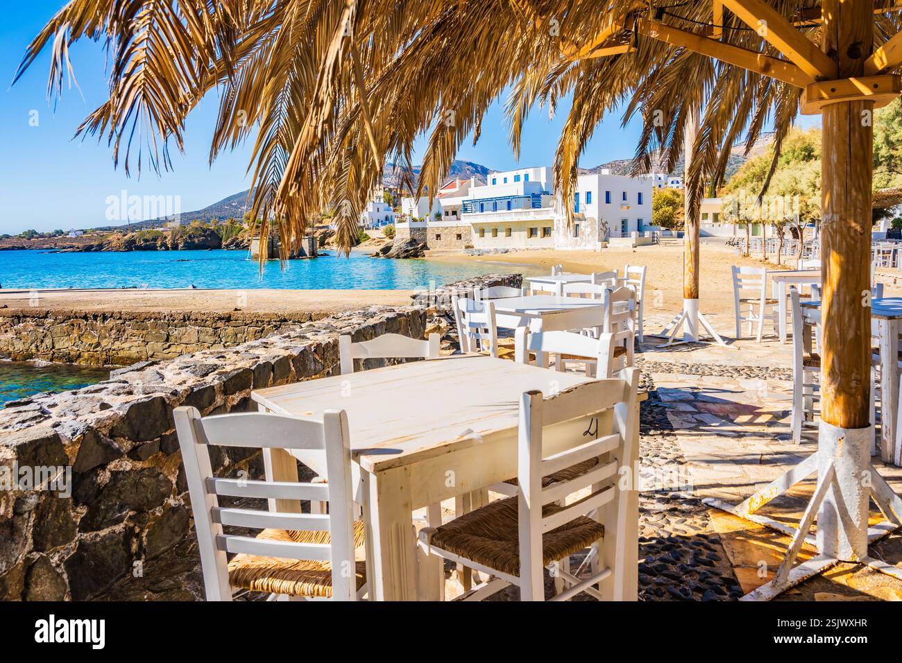Tavoli con sedie nel ristorante greco taverna sulla costa del mare nel villaggio di Motsouna, isola di Naxos, Cicladi, Grecia Foto Stock