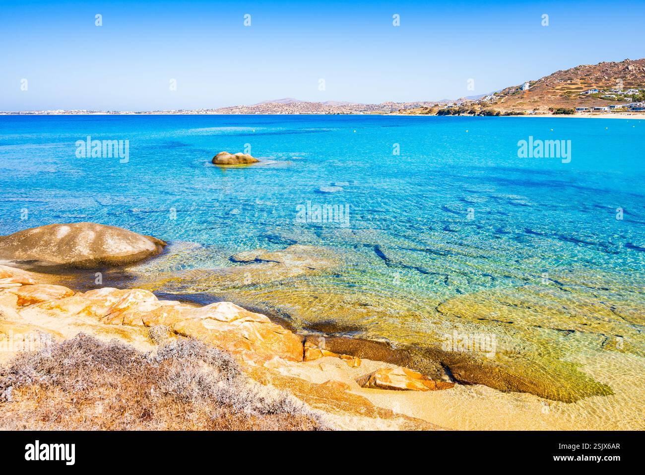 Rocce e pietre sull'idilliaca spiaggia sabbiosa della baia di Orkos e acque cristalline e cristalline, l'isola di Naxos, le Cicladi, la Grecia Foto Stock