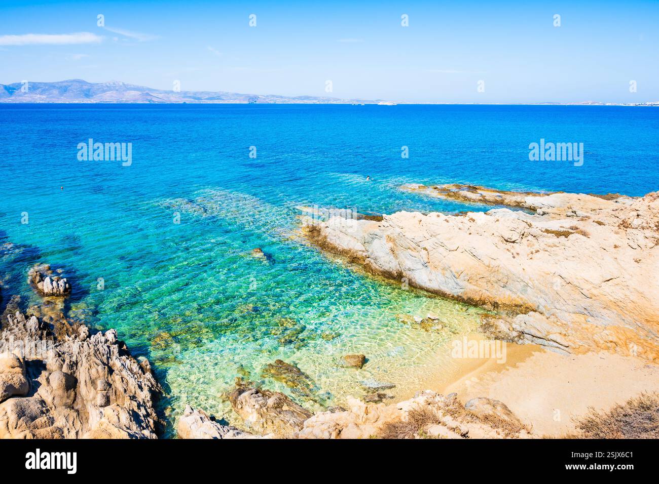 Rocce e pietre sull'idilliaca spiaggia sabbiosa della baia di Orkos e acque cristalline e cristalline, l'isola di Naxos, le Cicladi, la Grecia Foto Stock