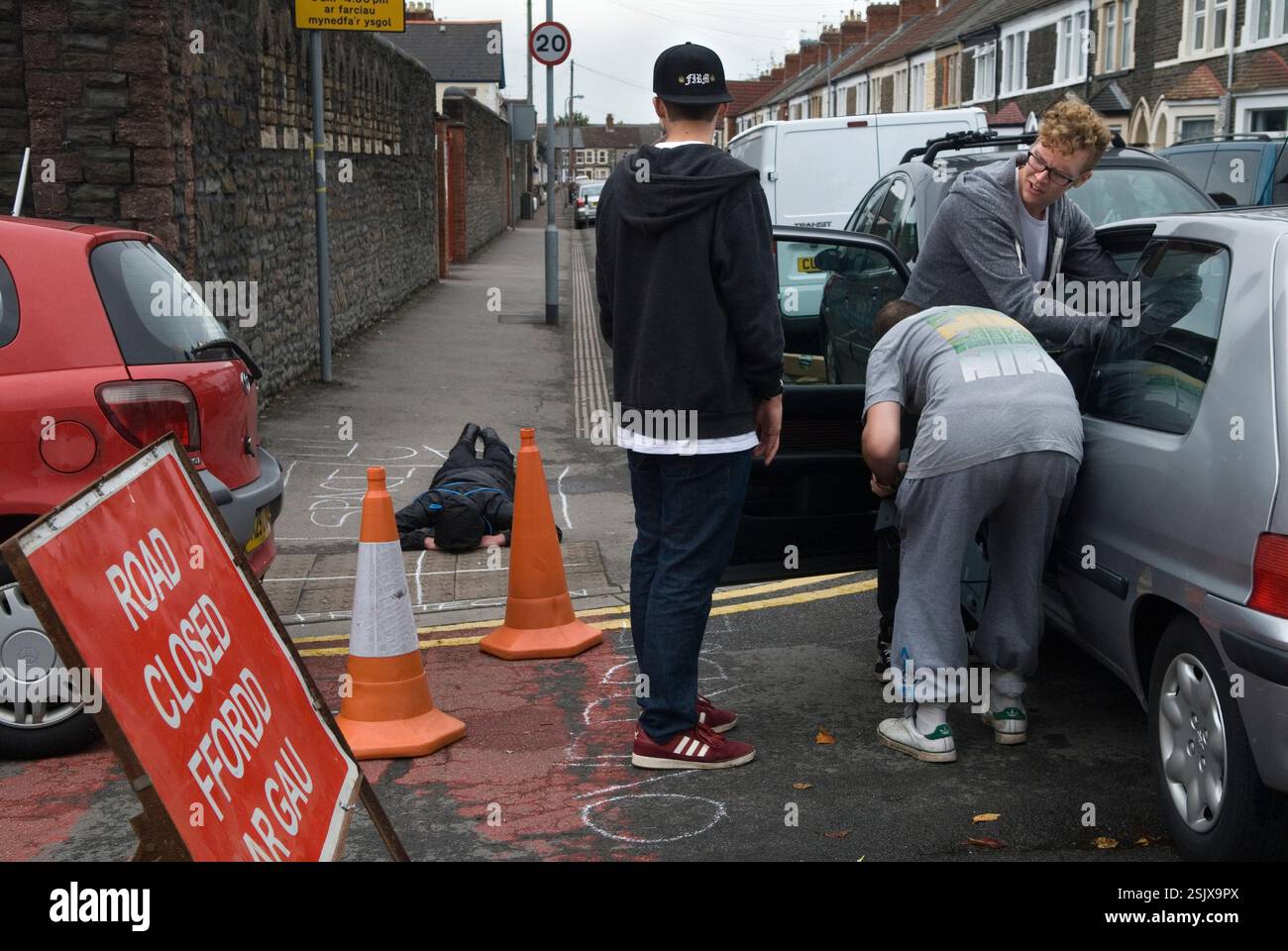 L'artista concettuale Craig sdraiato sul marciapiede "nel suo spazio". Community Arts Festival, Made in Spring Roath. Roath, Cardiff, Galles anni '2014 2010 UK HOMER SYKES Foto Stock