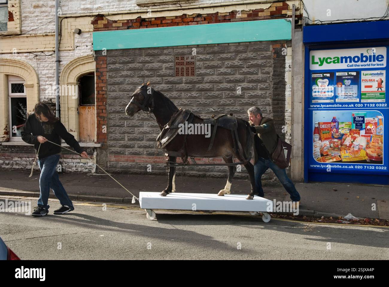 Lee Williams artista concettuale spingendo la sua opera d'arte chiamata "My Little Pit Pony". Collega che tira. L'opera d'arte rappresenta gli ex pony a fossa che sono andati giù nelle miniere di carbone in un tempo passato. Lo spingono e lo tirano intorno al quartiere. Partecipano a un festival annuale di arte della comunità chiamato Made in Spring Roath. Roath Cardiff, Galles anni '2014 2010 UK HOMER SYKES Foto Stock