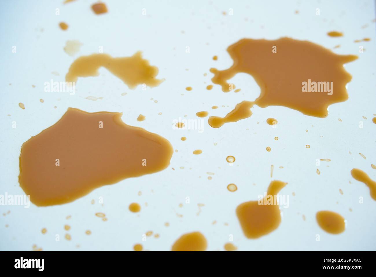 Le macchie di caffè su una superficie bianca creano un motivo astratto Foto Stock