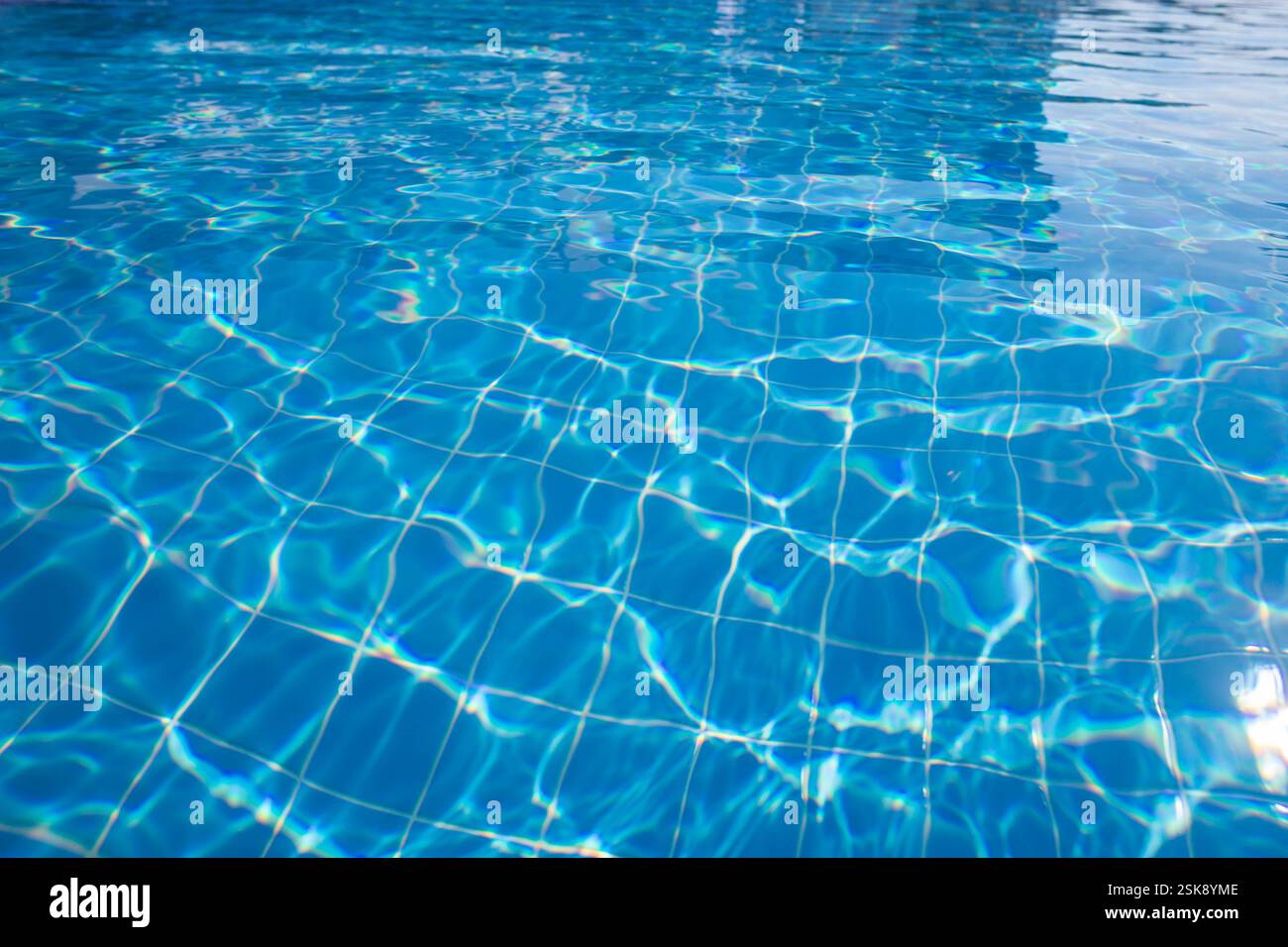 L'acqua della piscina, di colore blu brillante, riflette la luce del sole, crea un'atmosfera tranquilla e invitante in un ambiente soleggiato Foto Stock