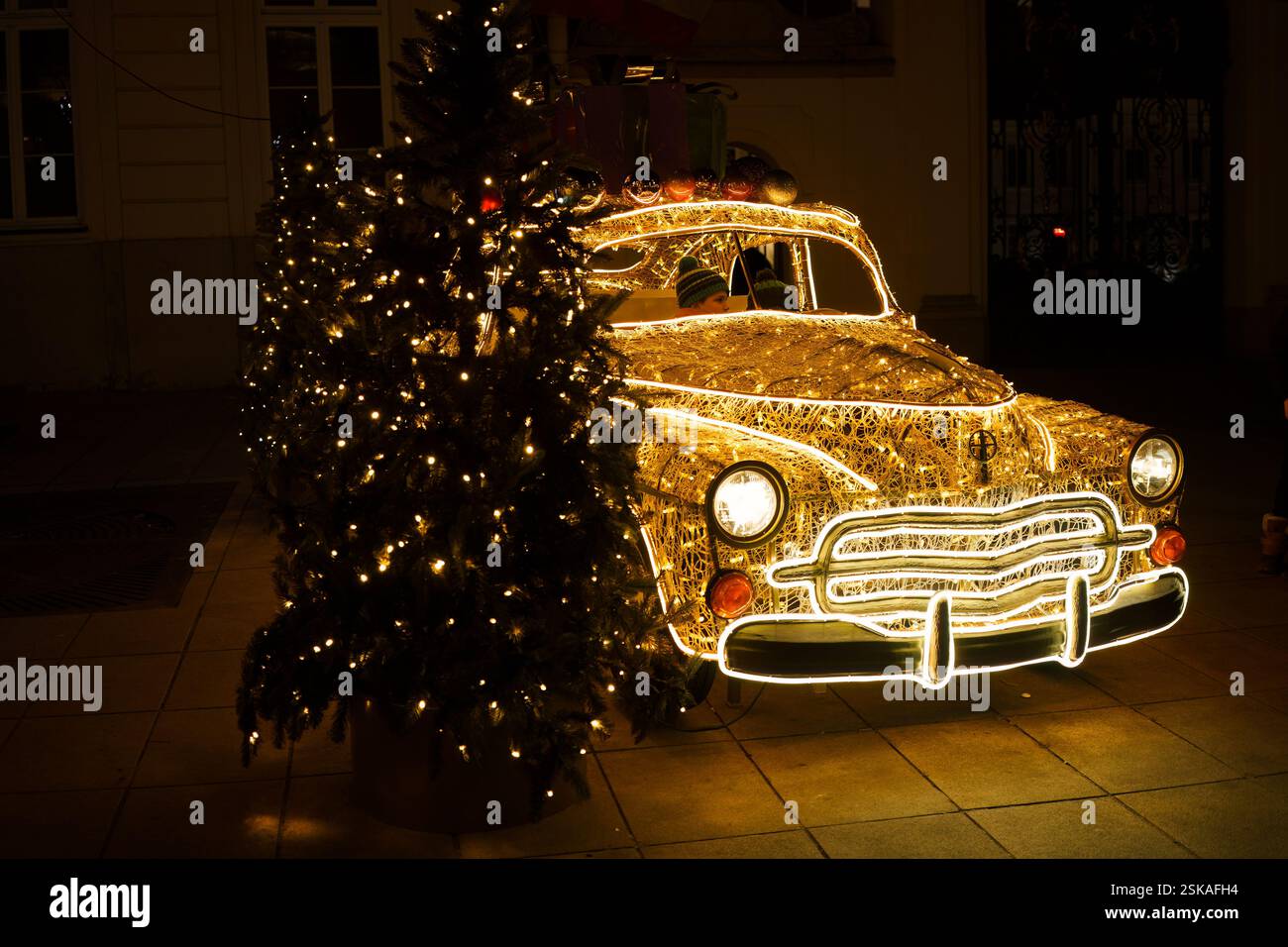 Varsavia, Polonia, 25 gennaio 2025 - installazione di luci natalizie a forma di auto d'epoca con bambini seduti all'interno. Foto Stock