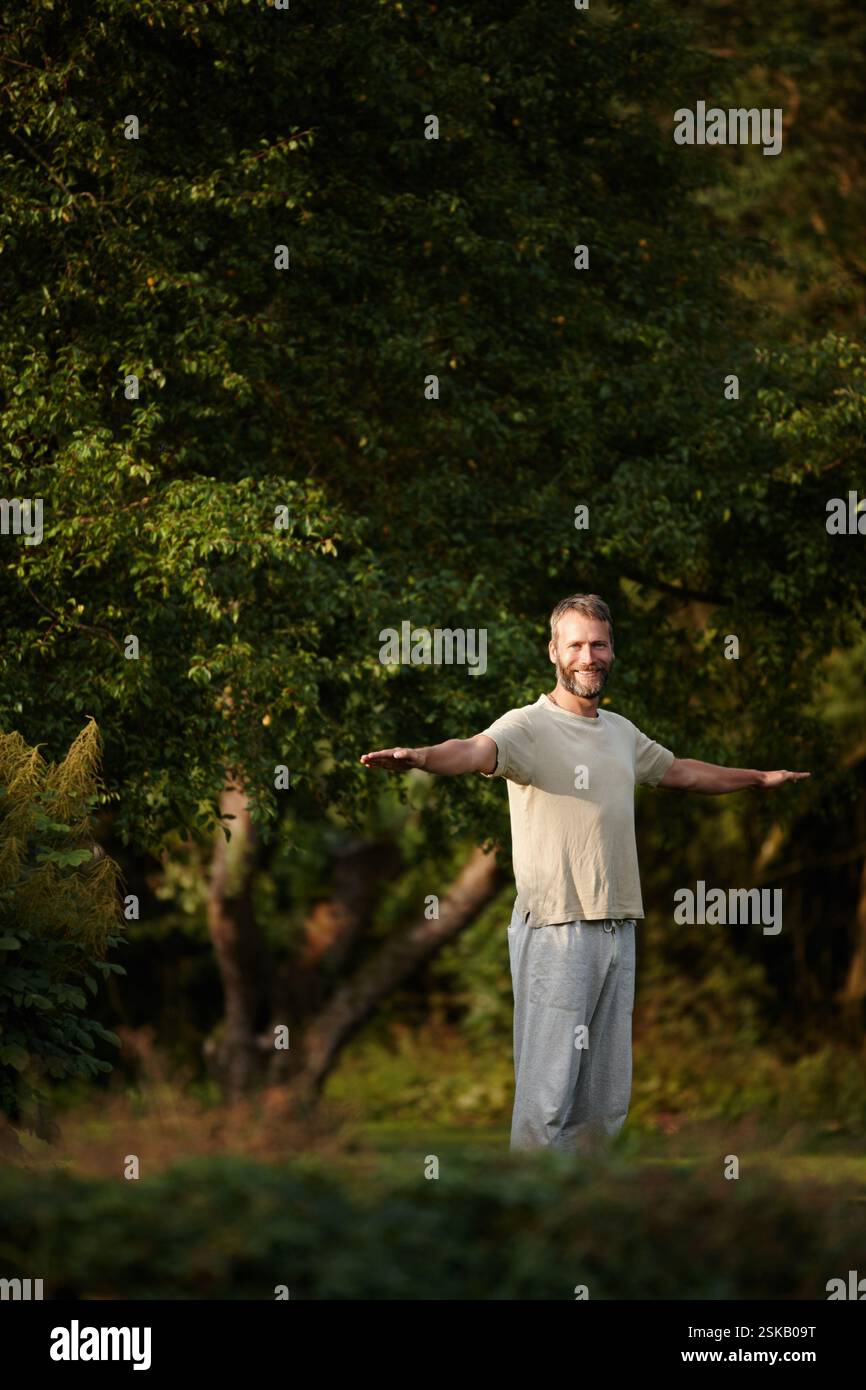 Ritratto, uomo e stretching per yoga su erba con consapevolezza, guarigione spirituale e pace in giardino. Sorridi, uomo e muscoli con riscaldamento per Foto Stock