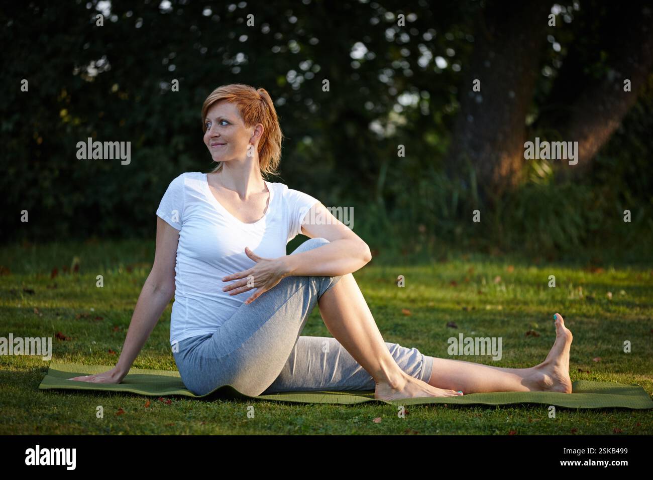 Sorridi, donna e stretching per lo yoga sull'erba per la consapevolezza, la guarigione spirituale e la pace in giardino. Pensiero, persona femminile e natura per il riscaldamento Foto Stock