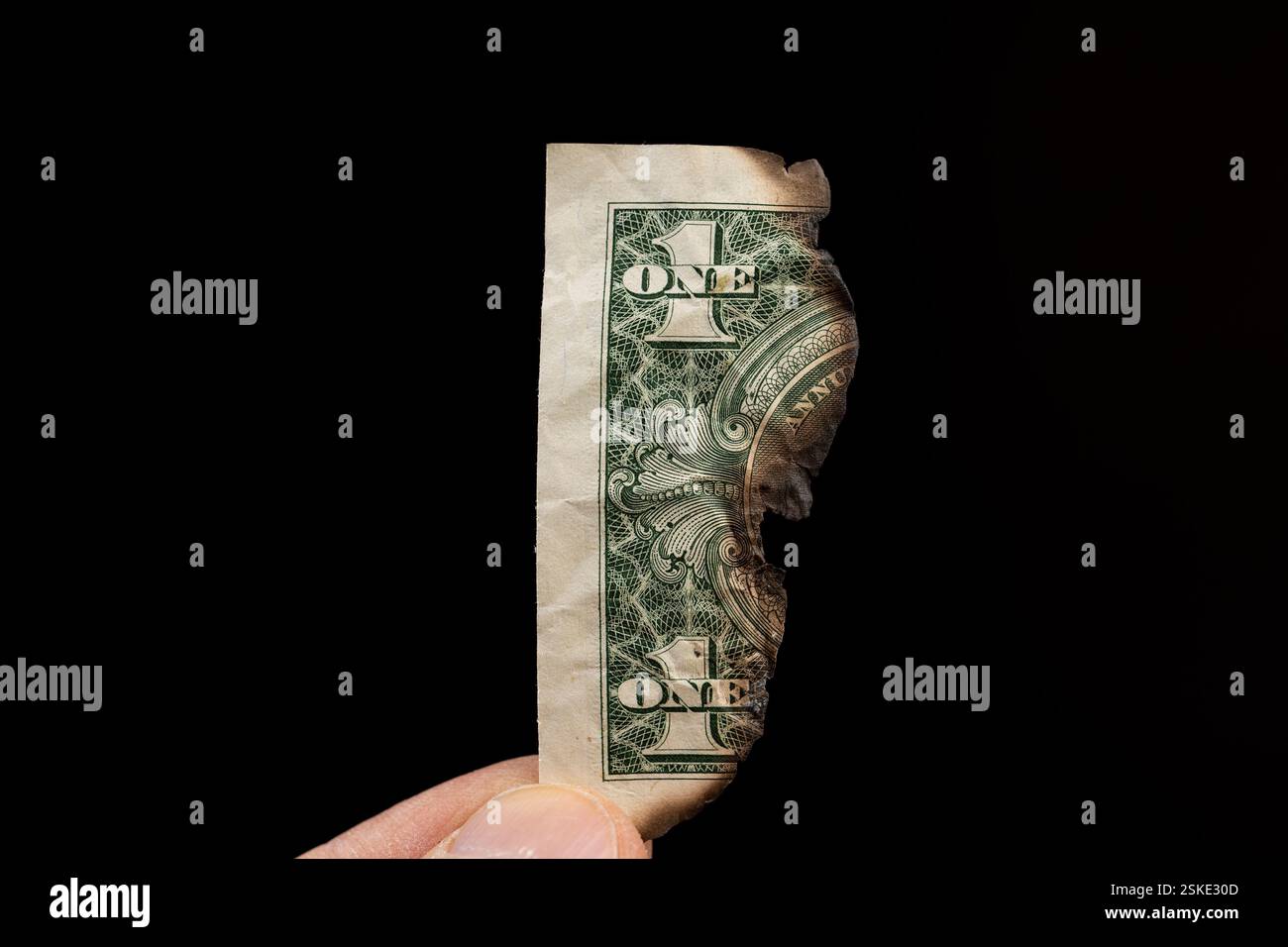 Dollari americani distrutti dal fuoco, una vecchia banconota di un dollaro americano in mano danneggiata dal fuoco Foto Stock
