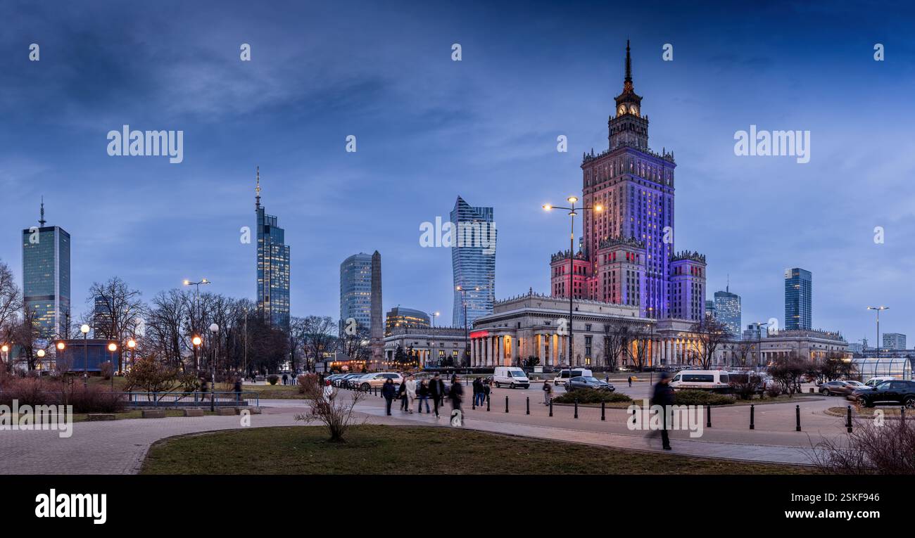 Notte a Varsavia, Polonia. Il Palazzo della Cultura e della Scienza è illuminato da vivaci luci rosse, blu e viola, a contrasto con il cielo scuro. Foto Stock