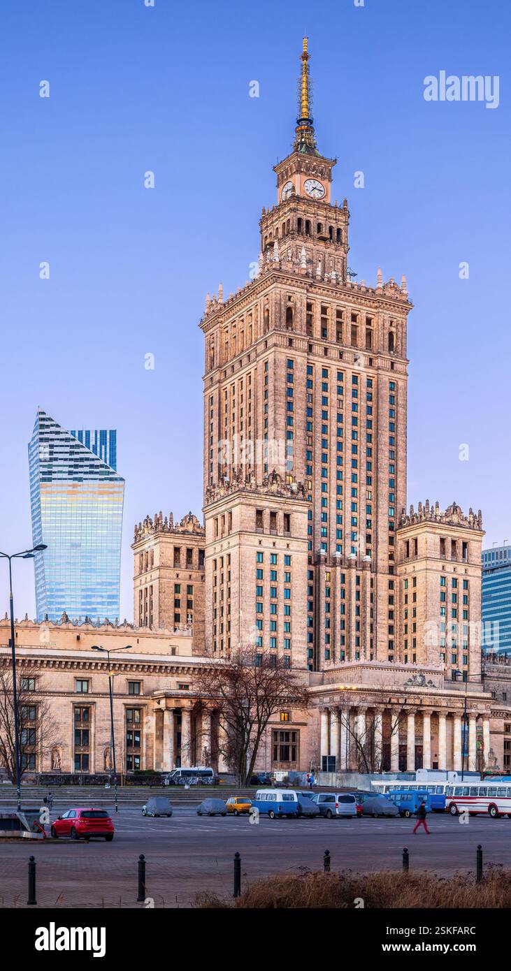Il centro di Varsavia prima dell'alba fonde i moderni grattacieli con l'iconico Palazzo della Cultura. I lampioni si illuminano, riflettendo sulle torri di vetro Foto Stock