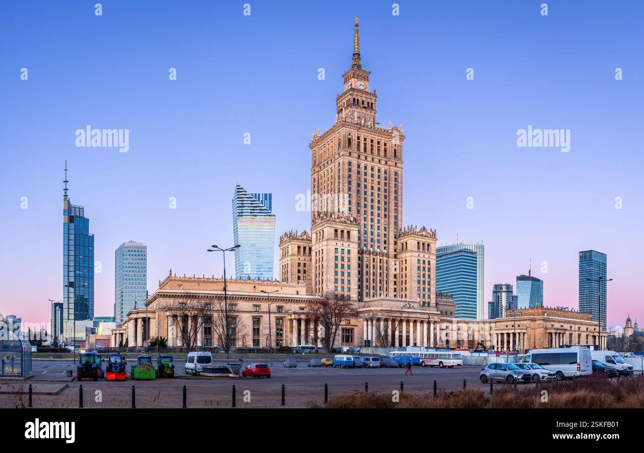 Il centro di Varsavia prima dell'alba fonde i moderni grattacieli con l'iconico Palazzo della Cultura. I lampioni si illuminano, riflettendo sulle torri di vetro Foto Stock