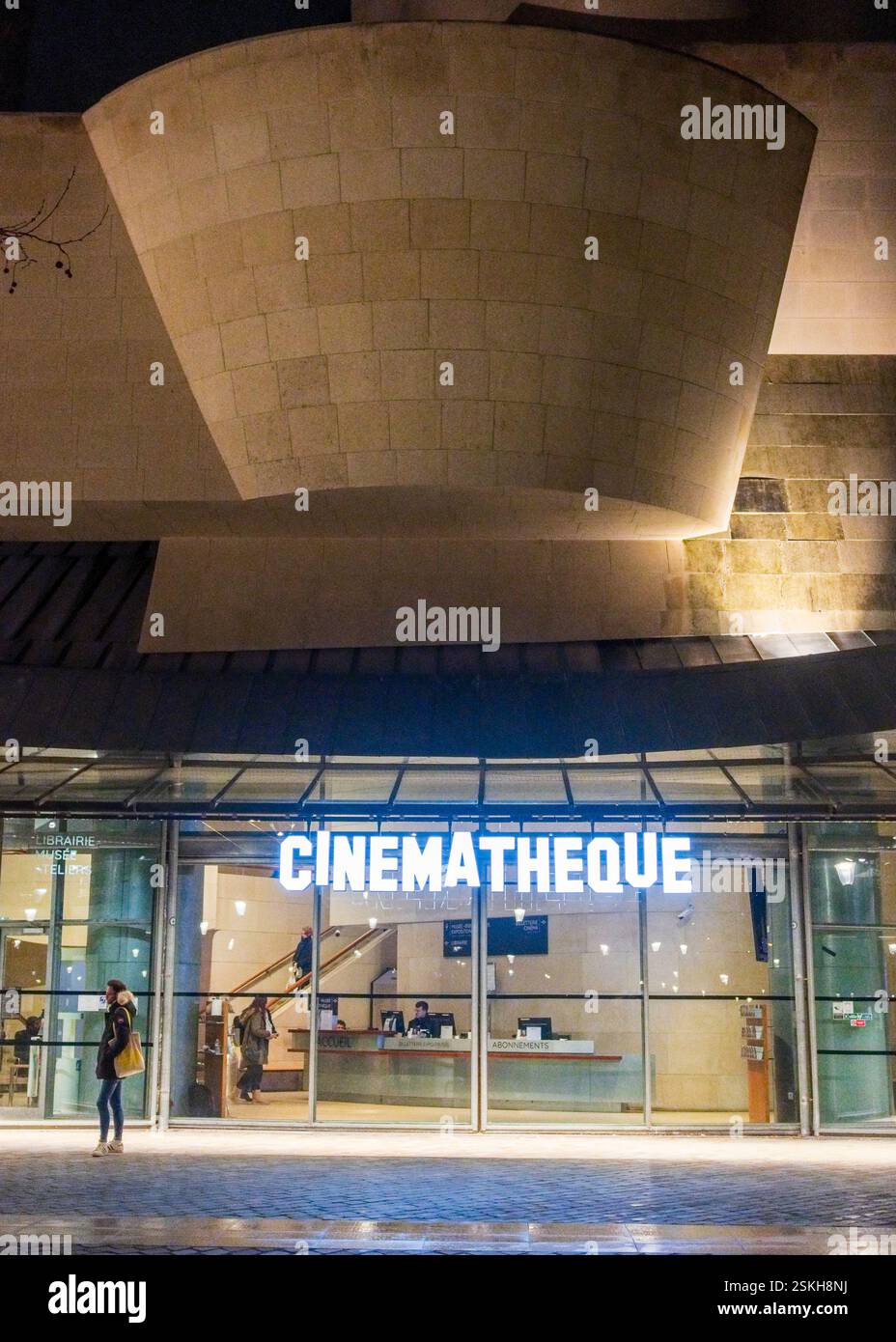 Ingresso moderno alla Cinematheque francese con suggestive curve architettoniche, un rinomato archivio cinematografico e centro culturale di Parigi illuminato di notte Foto Stock