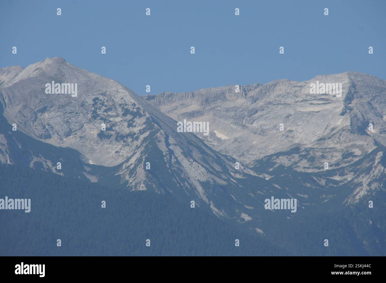 Catena montuosa, BULGARIA. Le cime innevate si innalzano sopra una valle, IN BULGARIA. Terreno accidentato. Un simbolo di forza e resilienza. Un ricordo del powe Foto Stock