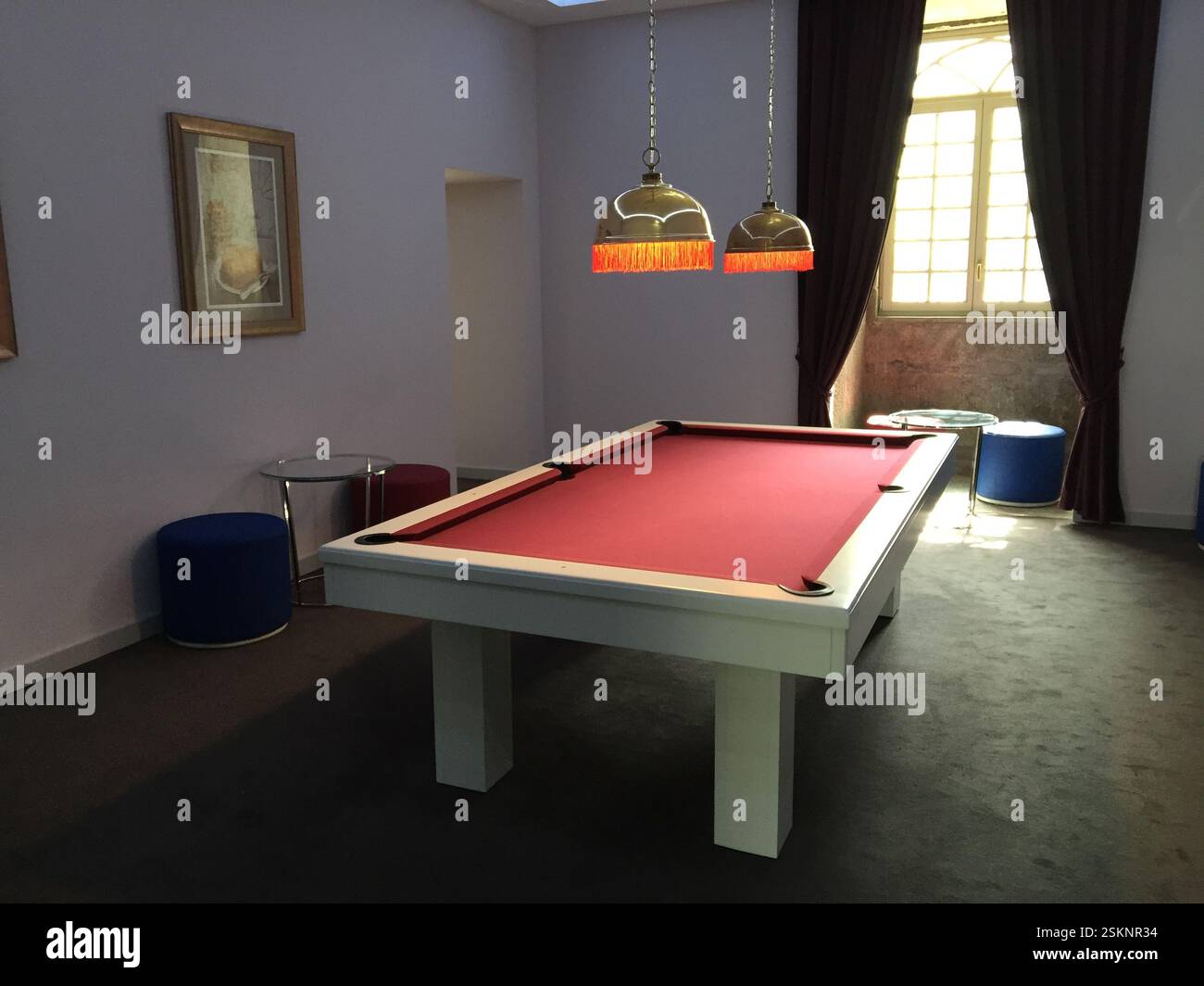 Tavolo da biliardo con feltro rosso, struttura in legno bianco e gambe in una sala ben illuminata, Braga, Portogallo. Una sala giochi classica ed elegante che trasuda fascino vintage, perfec Foto Stock