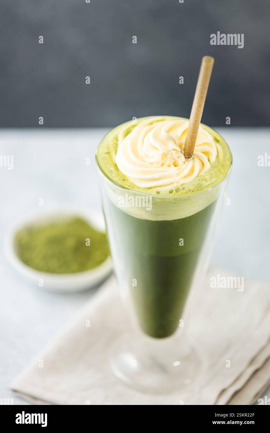 Rinfrescante latte matcha ghiacciato con panna montata e servito con una cannuccia eco-compatibile, promuovendo uno stile di vita sano e sostenibile Foto Stock