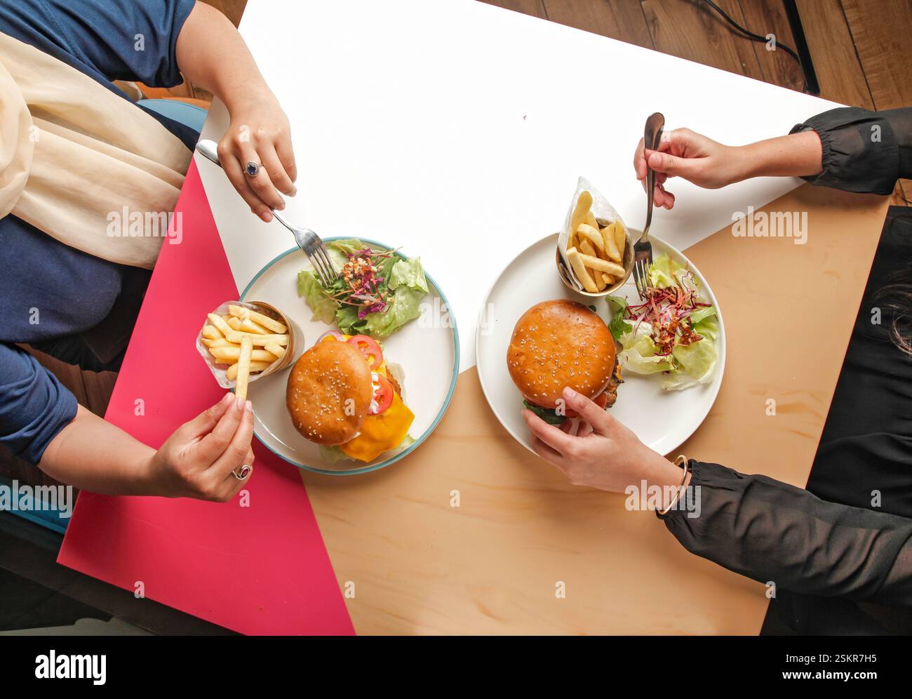 Fotografia di hamburger gourmet in un ambiente da caffetteria, amici che si godono un pasto insieme. Foto Stock