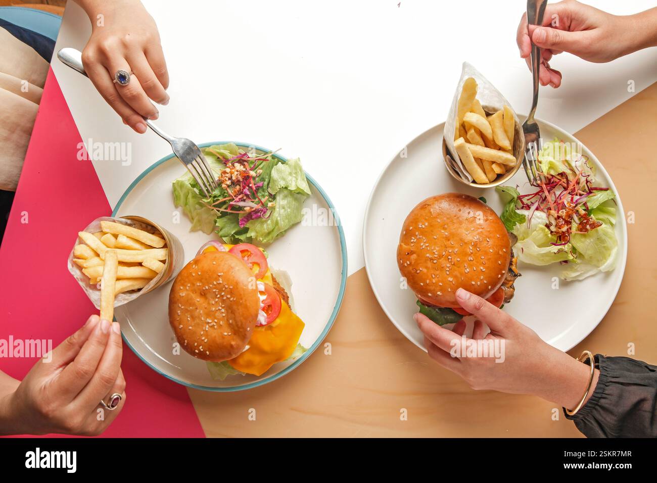 Fotografia di hamburger gourmet in un ambiente da caffetteria, amici che si godono un pasto insieme. Foto Stock