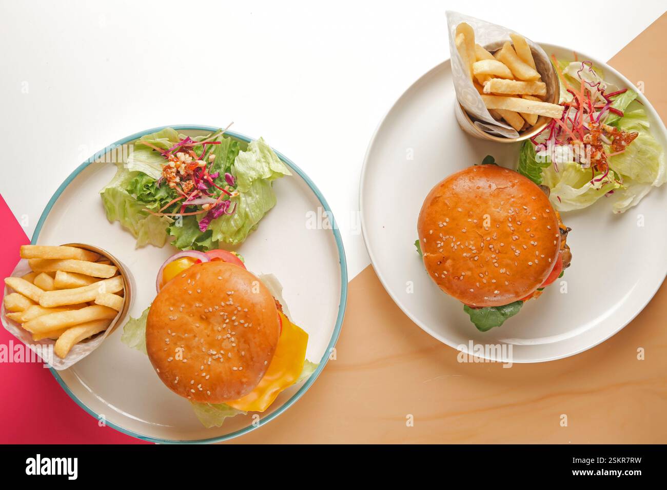 Hamburger gourmet di manzo e pollo fritto serviti con patatine fritte tagliate a mano su un bicchiere di metallo dorato e un pizzico di verdure. Foto Stock