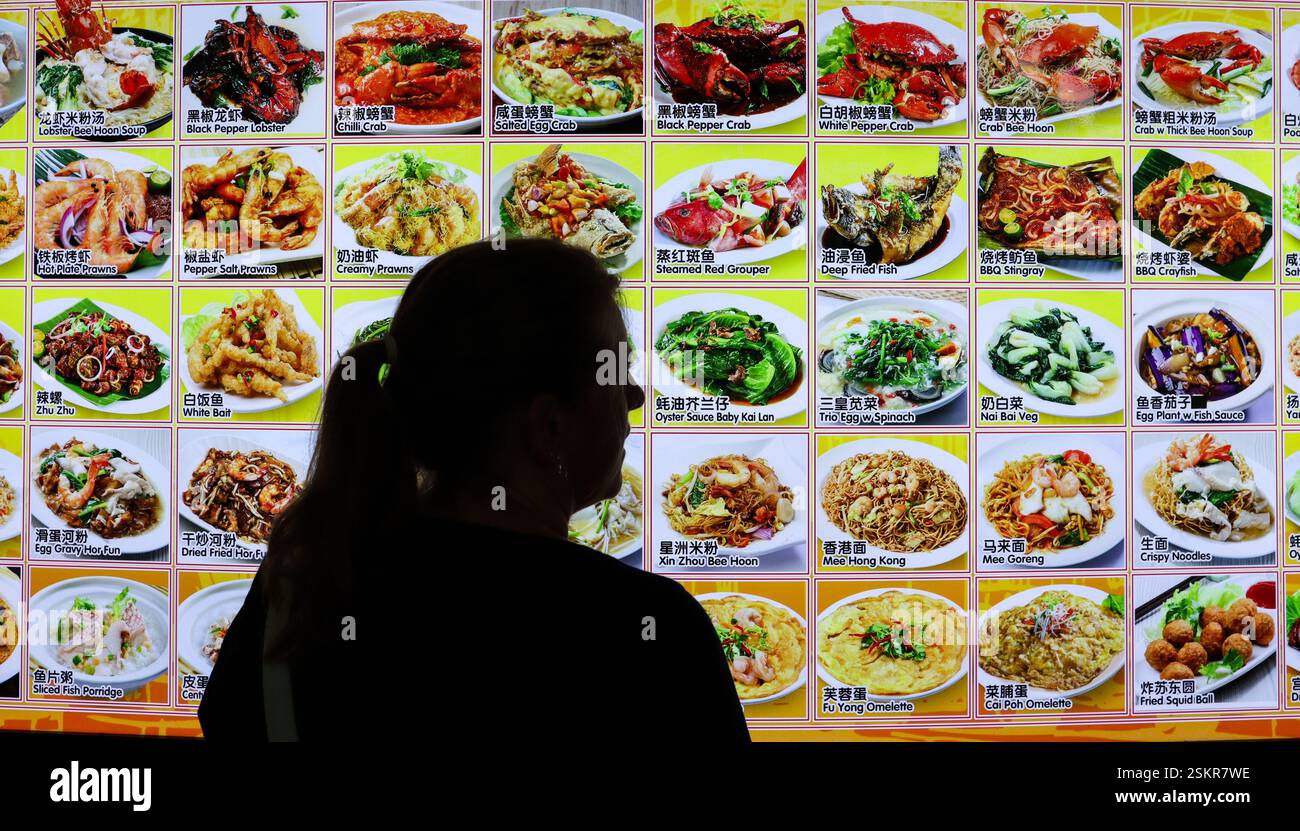 Un turista che guarda la scelta di cibo di strada a Satay bu The Bay, Singapore. Foto Stock