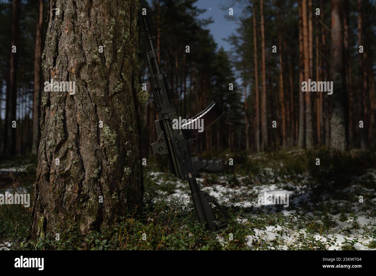 Un moderno fucile d'assalto russo con vista olografica si trova vicino a un albero in una foresta notturna. Foto Stock