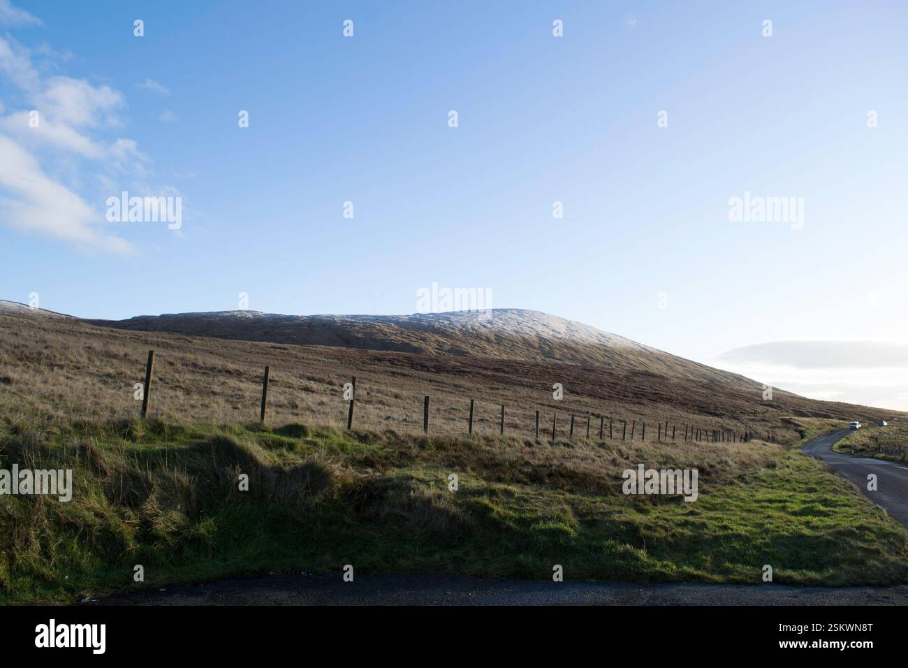 Una vista delle montagne di Mourne con una recinzione e una strada come linee guida Foto Stock