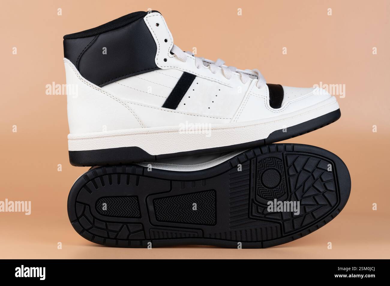 Sneaker alte dal design elegante bianco e nero, con superficie di colore neutro per un'enfasi particolare. Foto Stock